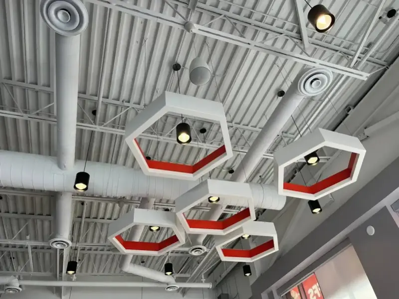 Exposed HVAC ductwork, air diffusers, and pendant lighting on an open ceiling at Mr. Puffs Café in Vaughan.
